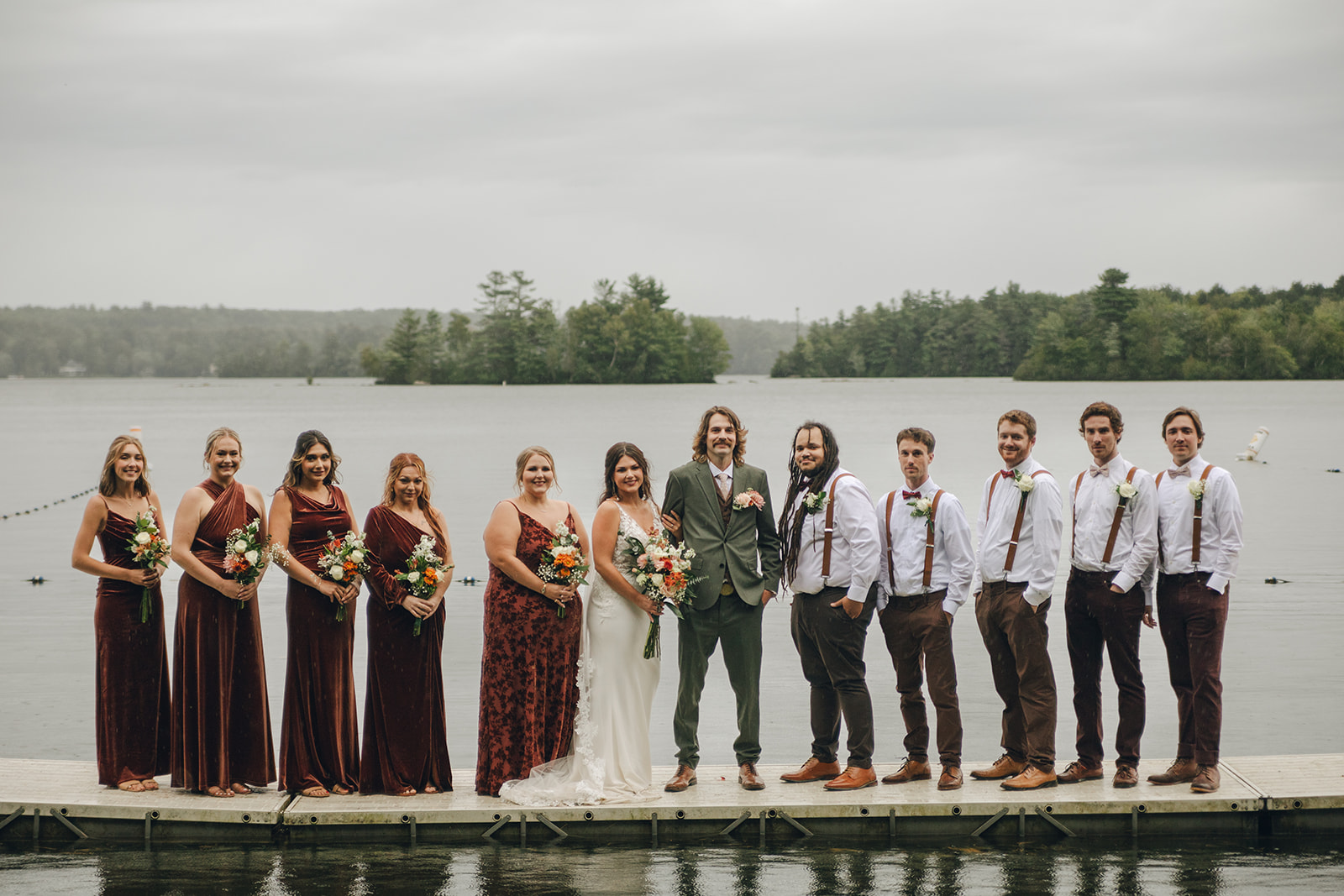 bride, groom and their wedding party stand on a dock in Winthrop, Maine